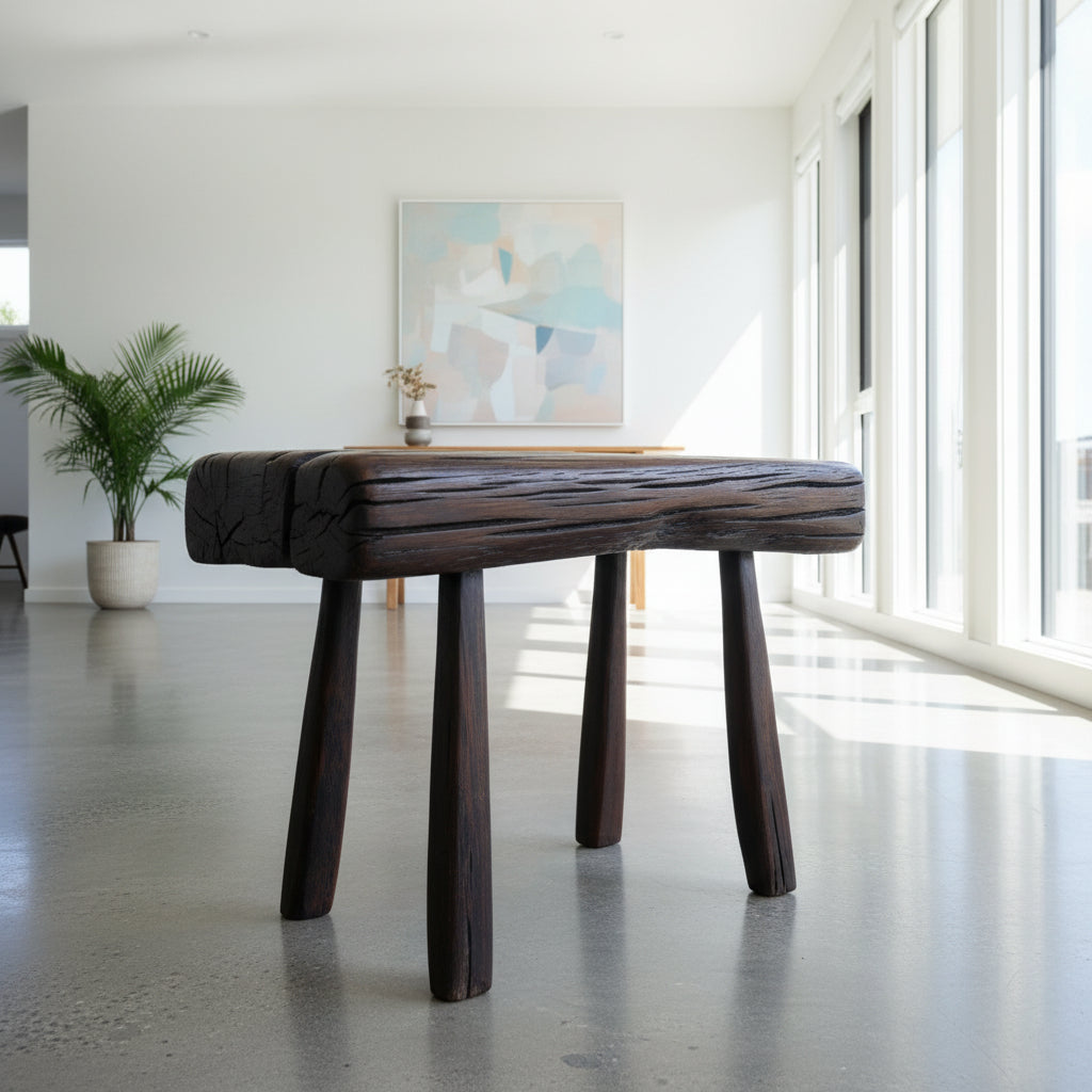 Wooden stool on a white surface with a concrete floor in the background