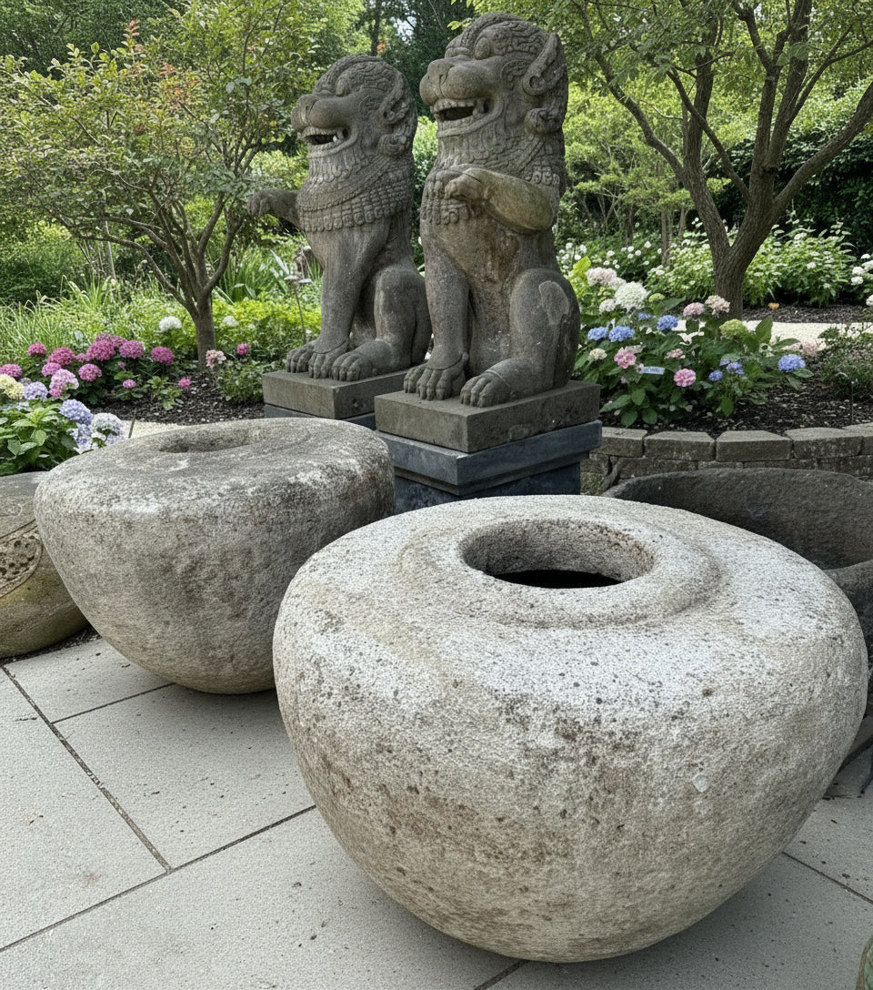 Two large garden pots in the foreground with two large guardian lions in the background in a beautiful garden