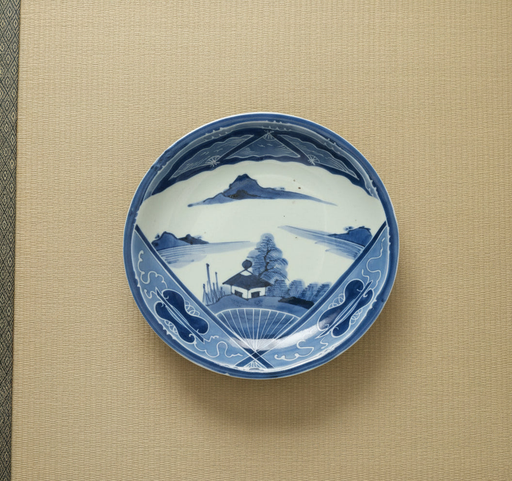 Japanese underglaze blue and white plate with a fan design, featuring a landscape and a traditional Japanese house.