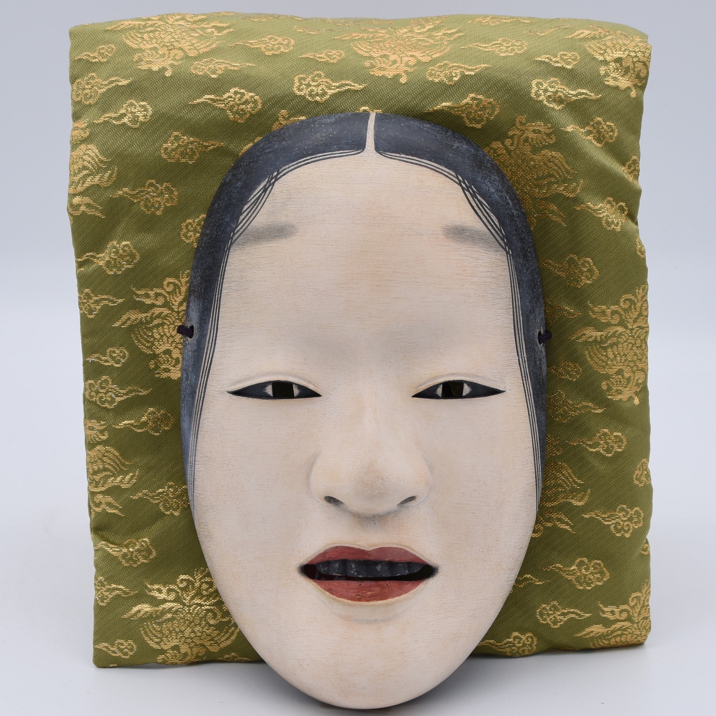 An antique Japanese Noh mask of Zo-Onna, it is believed that the name "Zo-onna" was named by it's creator Zo-ami. Unlike Ko-omote or Waka-onna, the mask does not display joy or cuteness. Instead, it reflects calmness, purity, and peaceful images of deities of ancient Japan.

Noh masks are carved from Japanese cypress (hinoki) using traditional chisels and templates and finished with the crushed shell powder (gofun), animal glue (nikawa), and mineral pigments (iwa-enogu), the same materials used in tradition