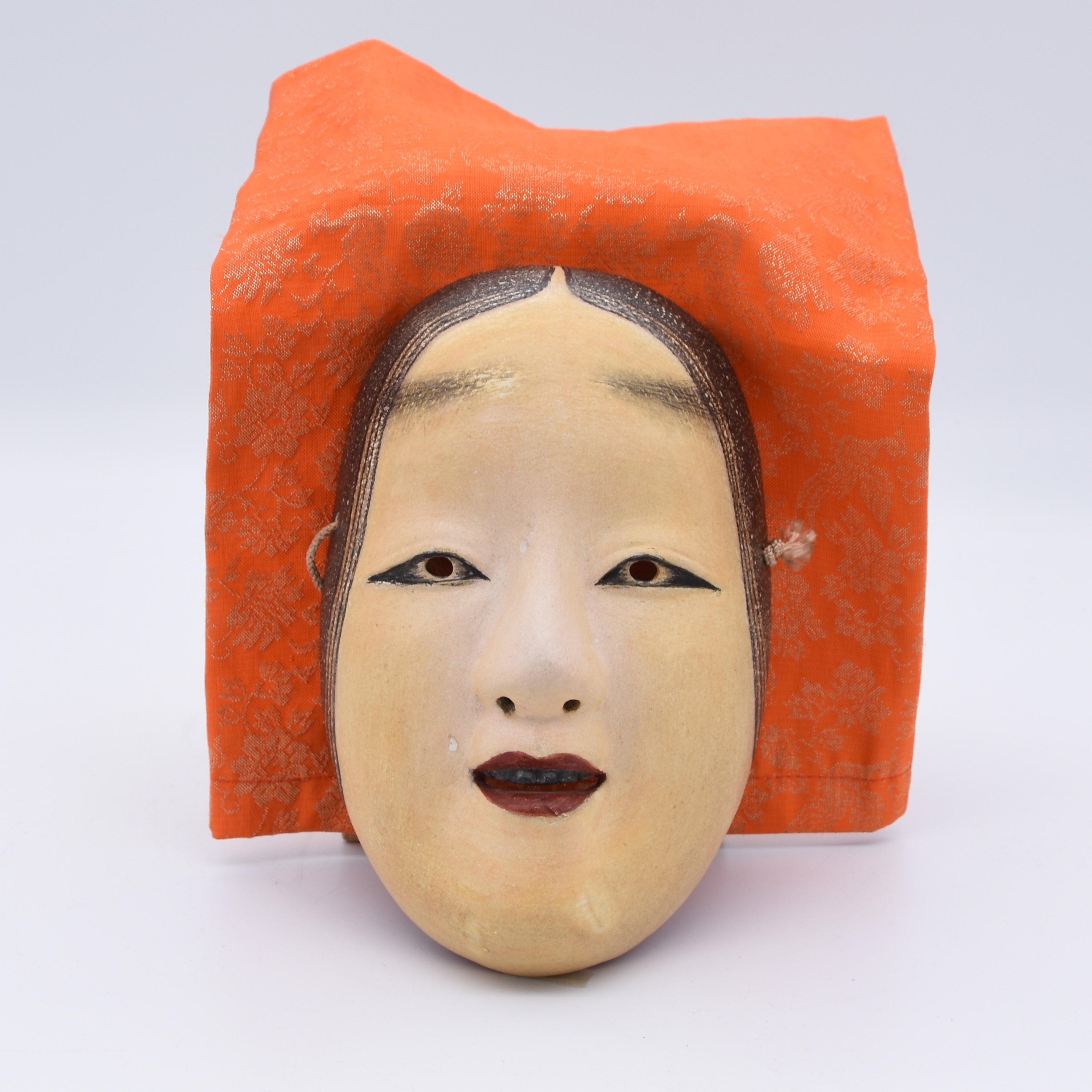 An antique Japanese Noh mask of Zo-Onna, it is believed that the name "Zo-onna" was named by it's creator Zo-ami. Unlike Ko-omote or Waka-onna, the mask does not display joy or cuteness. Instead, it reflects calmness, purity, and peaceful images of deities of ancient Japan.

Noh masks are carved from Japanese cypress (hinoki) using traditional chisels and templates and finished with the crushed shell powder (gofun), animal glue (nikawa), and mineral pigments (iwa-enogu), the same materials used in tradition
