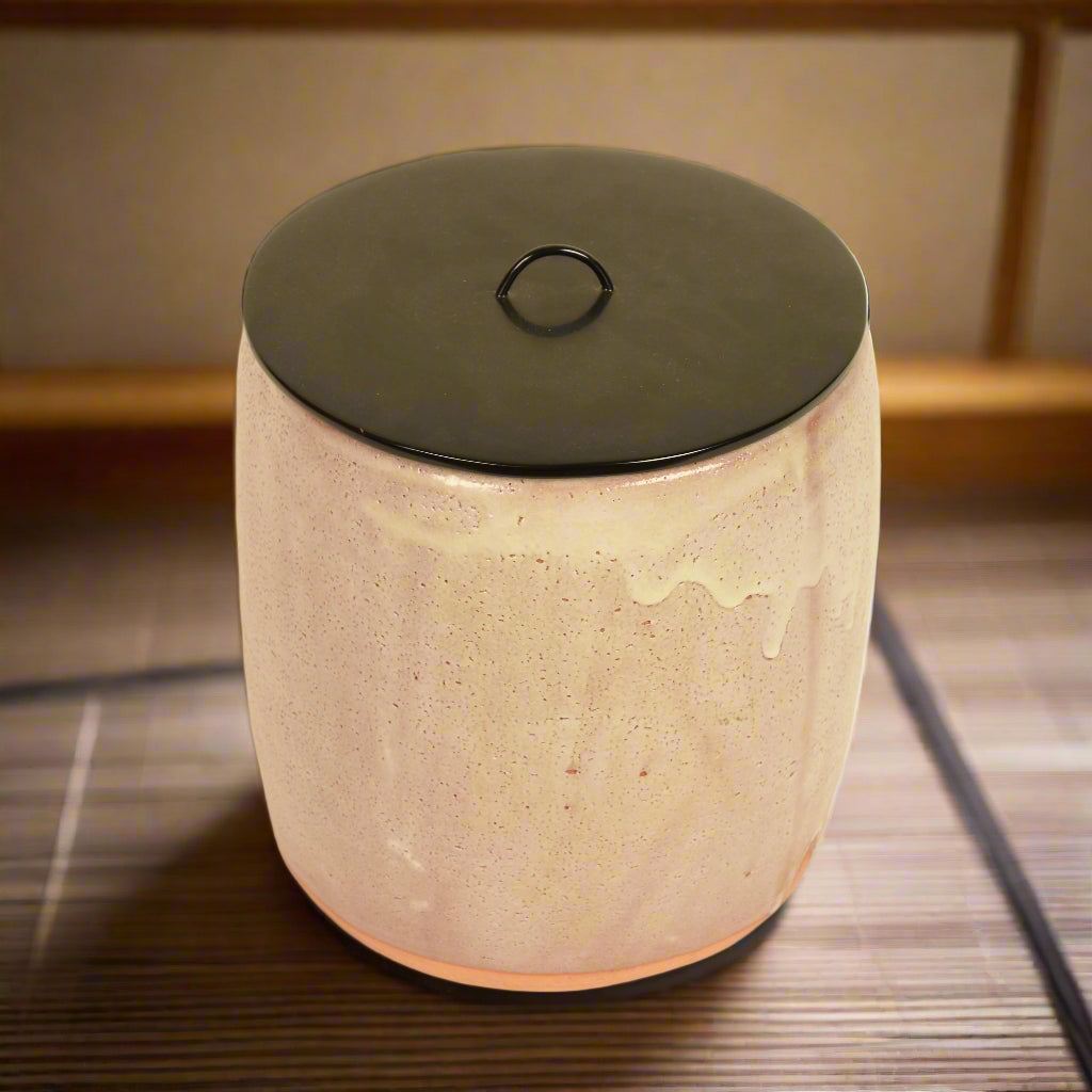 A Japanese Shino pottery mizusashi with an opaque white drip glaze and black lacquer lid.
